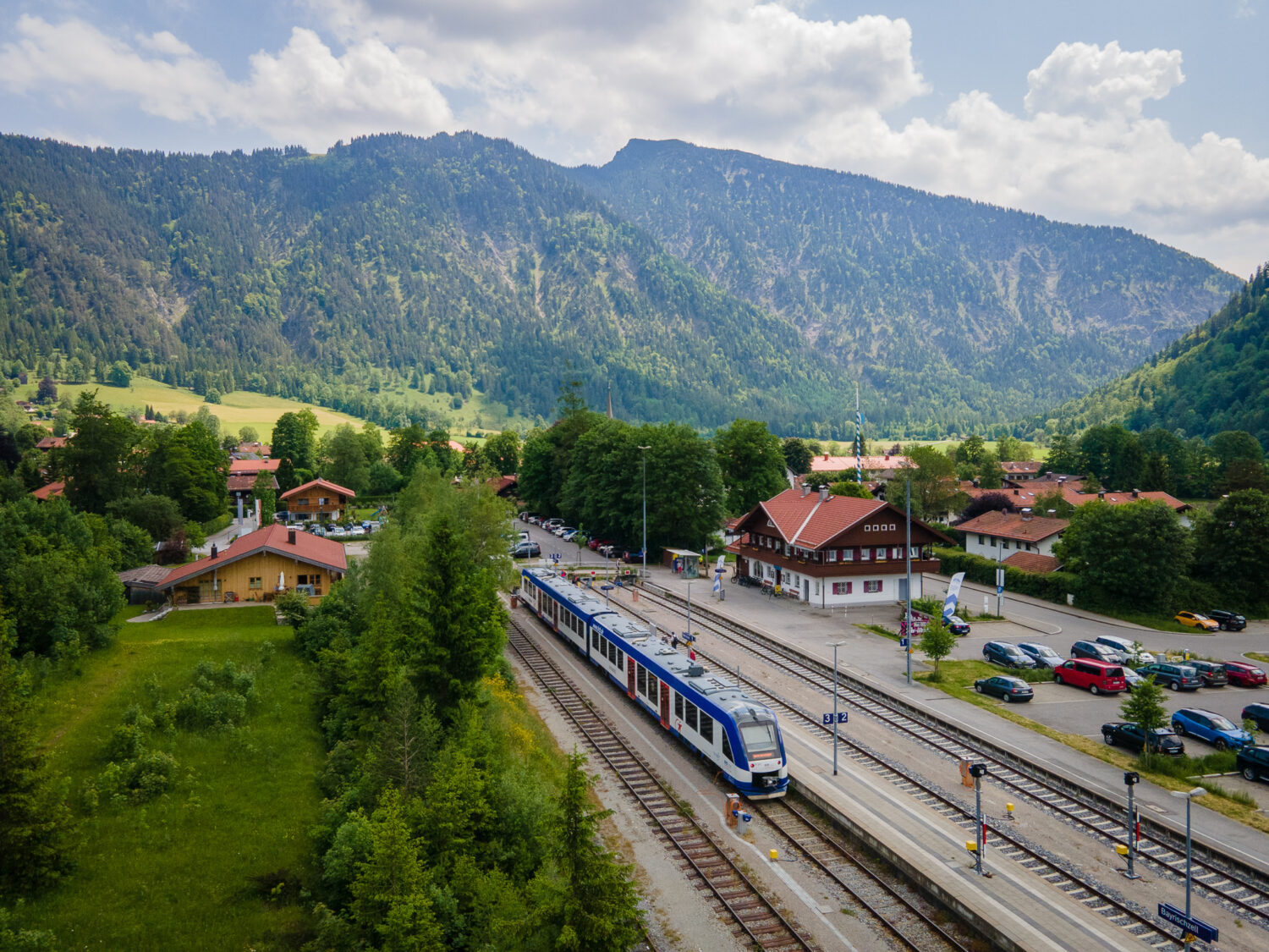 Bahnstrecke im Zug im Leitzachtal. Bewaldete Berge im Hintergrund.